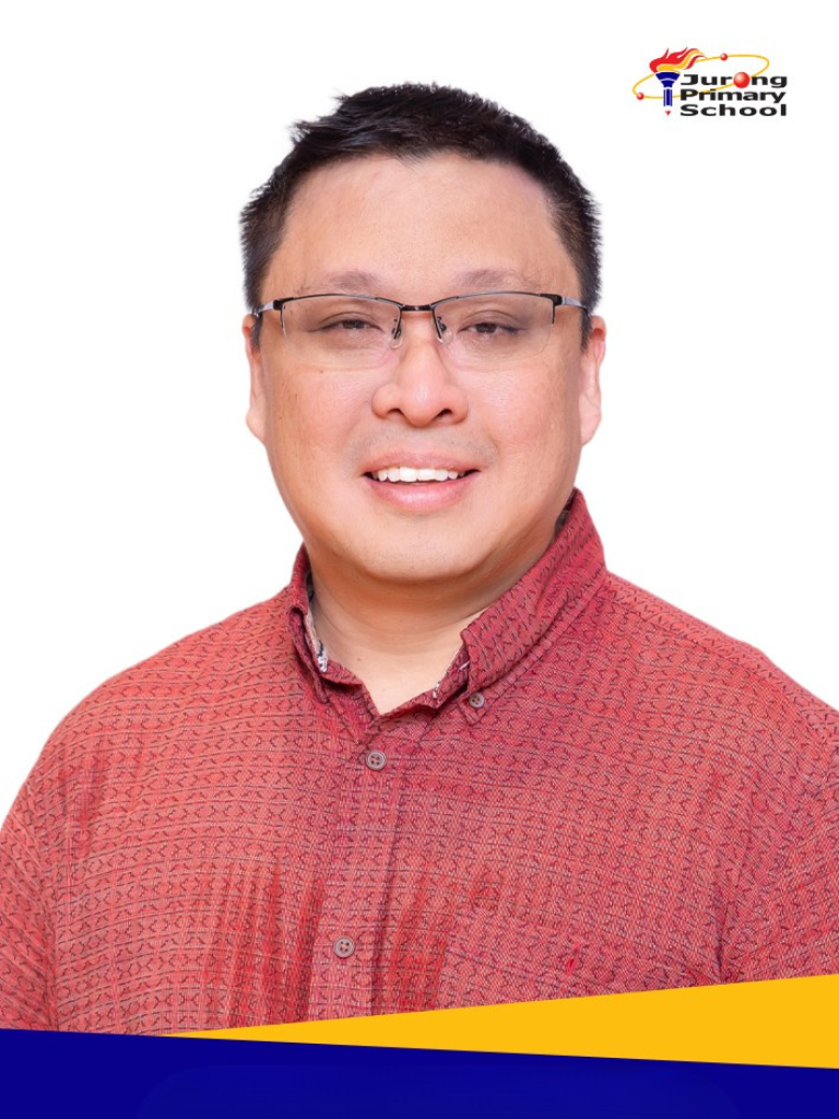 Smiling man in red patterned shirt, glasses, short dark hair.
